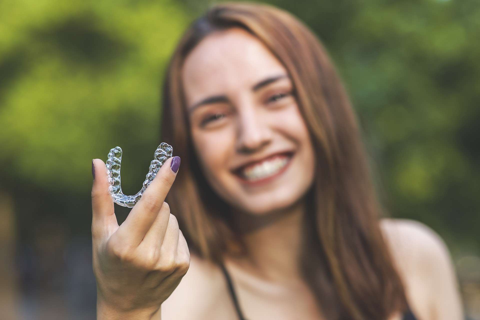 Smiling woman is holding an clear aligners