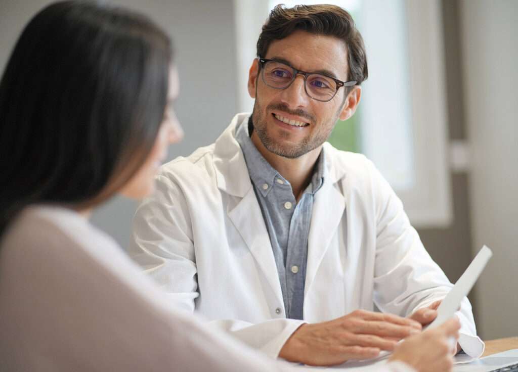 Modern young doctor speaking to patient in office