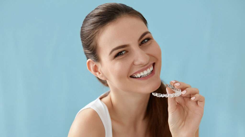 Dental care. Smiling woman using removable clear teeth braces