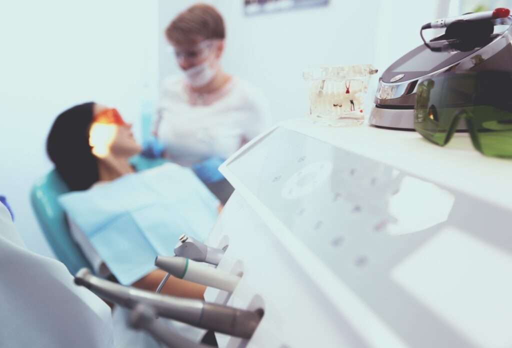 Woman sitting in an orthodontic exam room with a doctor and machinery.