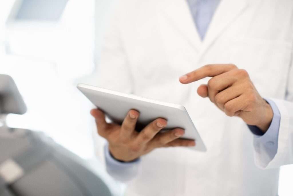 Man in a white coat using a tablet.